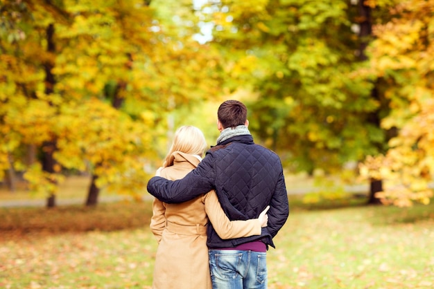 liefde, relatie, familie en mensenconcept - paar knuffelen in herfstpark van achteren