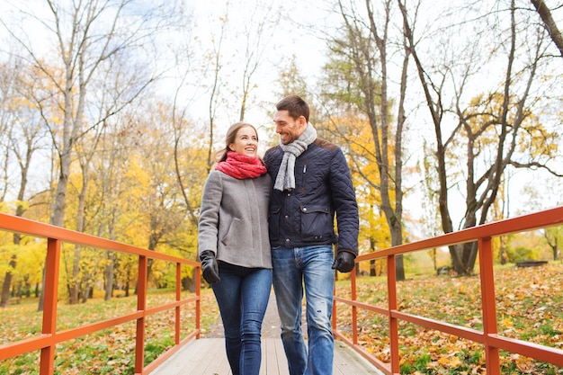 liefde, relatie, familie, seizoen en mensenconcept - glimlachend paar knuffelen op brug in herfstpark