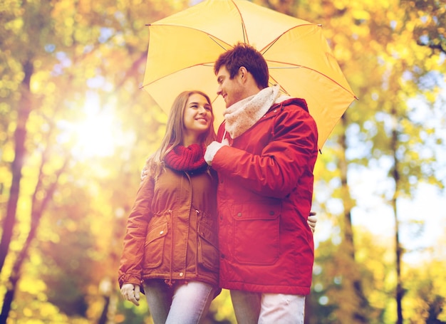 liefde, relatie, seizoen, gezin en mensen concept - gelukkig stel met paraplu wandelen in het herfstpark