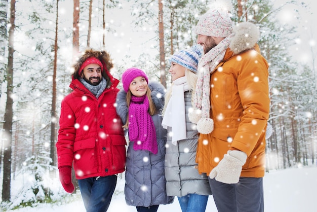 liefde, relatie, seizoen, vriendschap en mensenconcept - groep glimlachende mannen en vrouwen die in het winterbos praten