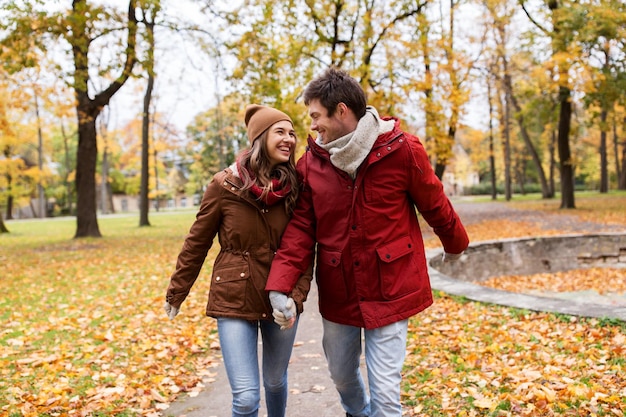 liefde, relaties, seizoen en mensenconcept - gelukkig jong stel wandelend in het herfstpark en pratend