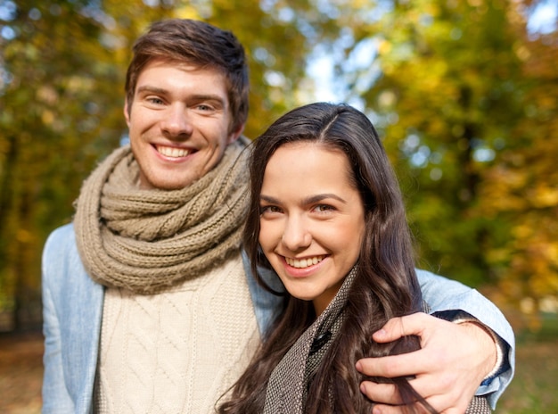 Liefde, verhoudings, familie en mensenconcept - glimlachend paar die in de herfstpark koesteren