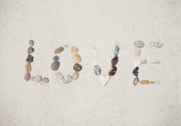 Liefdebericht dat van kiezelsteen op het strand van de zandzomer wordt gemaakt