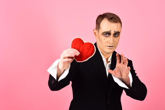 Liefdesbekentenis op Valentijnsdag Theateracteur pantomime verliefd Mime-acteur met liefdesymbool Mime-man houdt rood hart vast voor Valentijnsdag Een artistieke uitdrukking