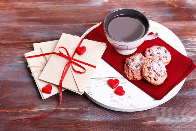 Liefdesbrieven met koffie en koekjes op houten achtergrond