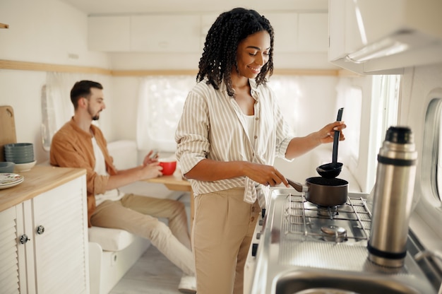 Liefdeskoppel koken in de keuken van de camper, kamperen in een aanhangwagen. Man en vrouw reizen op busje, vakanties op camper, kampeerders vrije tijd in kampeerauto