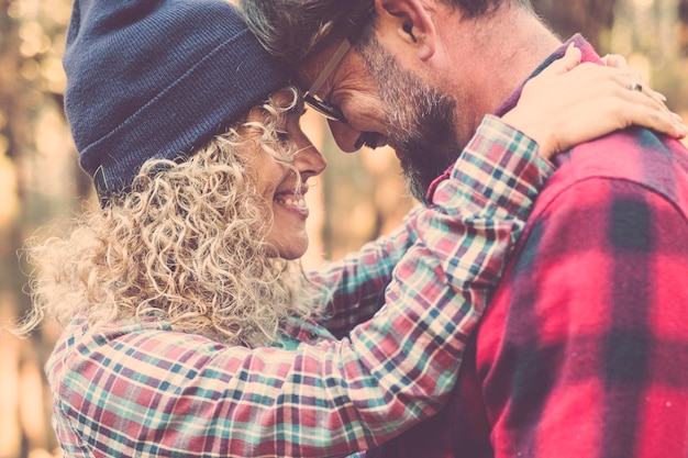 Foto liefdespaar en buiten natuur romantische vrijetijdsactiviteit samen man en vrouw knuffelen en omhelzen elkaar met emoties met bossen op de achtergrond vreugde getrouwde levensstijl mensen