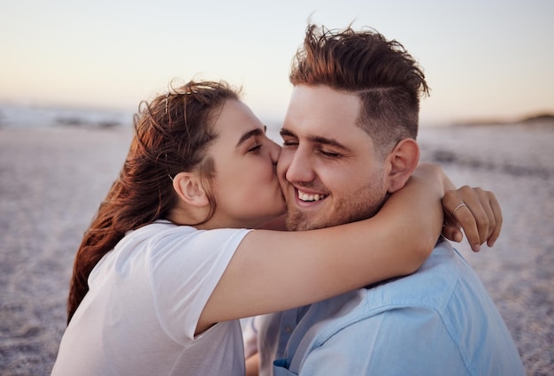 Liefdespaar en kus op het strand blij om relatie te vieren met zonsondergang ontspannen glimlach en op vakantie Romantiek man en vrouw omhelzen omhelzing en hechting op vakantie aan zee samen buiten