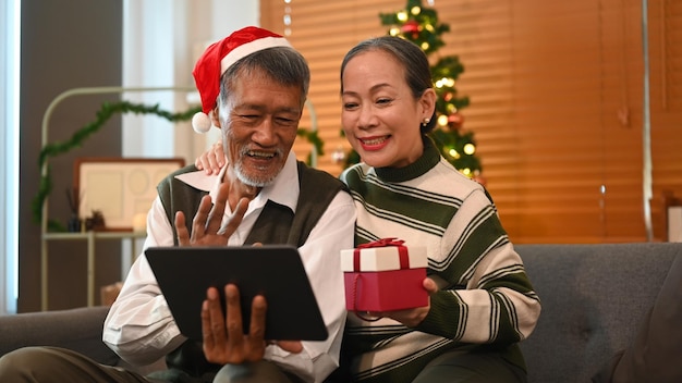 Liefdevol senior koppel met videogesprek met vrienden of familie op digitale tablet tugether in kerstvakantie