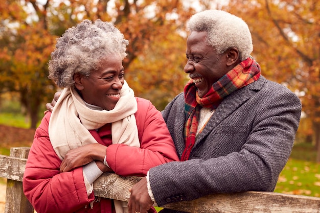 Liefdevol senior koppel op wandeling door herfstlandschap rustend bij poort