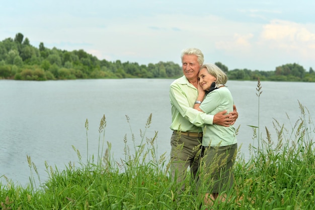 Liefdevol volwassen stel in de buurt van het meer in de zomer