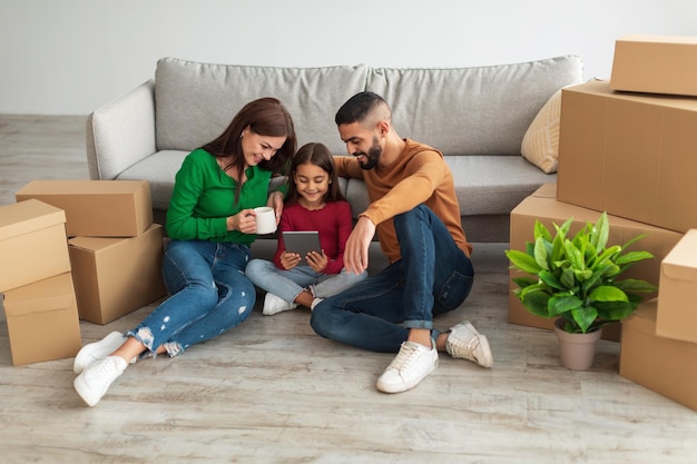 Liefdevolle Arabische familie die tablet gebruikt in hun nieuwe appartement