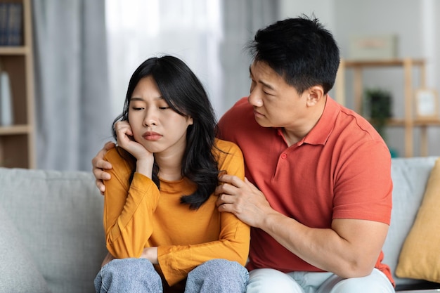 Liefdevolle Aziatische man troost zijn overstuur vrouw