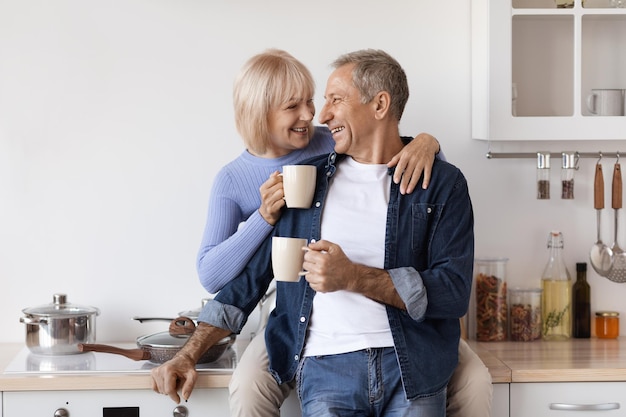 Liefdevolle bejaarde echtpaar genieten van koffie in de ochtend thuis