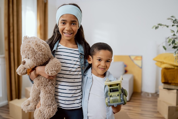 Liefdevolle broers en zussen staan tegen de achtergrond van het nieuw gekochte appartement van hun ouders dat intrekt