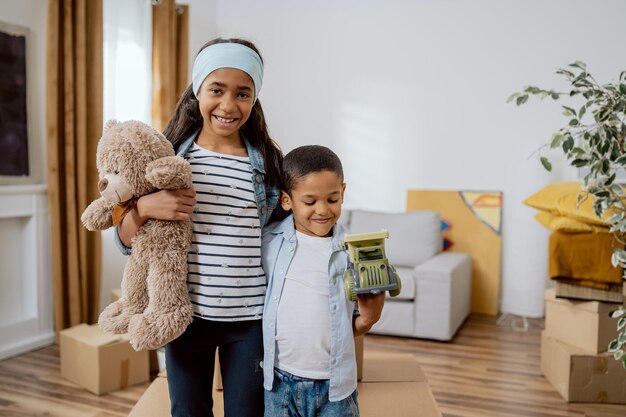 Liefdevolle broers en zussen staan tegen de achtergrond van het nieuw gekochte appartement van hun ouders dat intrekt