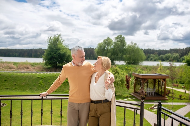 Liefdevolle echtgenoot en zijn elegante vrouw staan op het terras