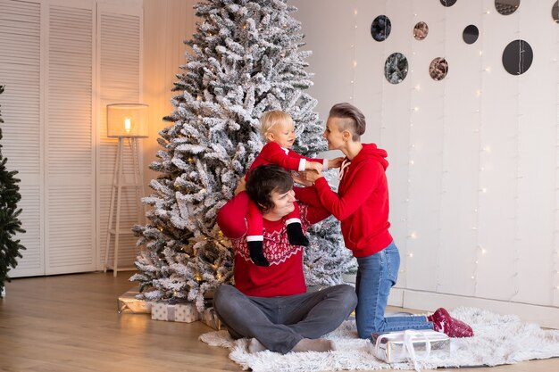 Liefdevolle familie met cadeautjes op de kamer. Prettige kerstdagen en fijne feestdagen. Ouders en hun kleine kind hebben plezier binnenshuis.