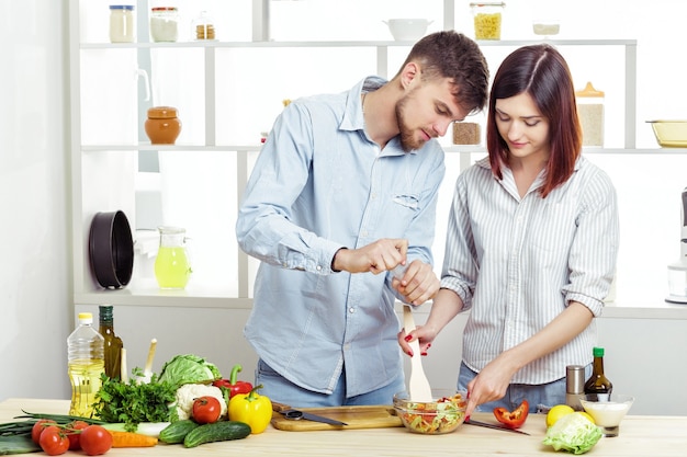 Liefdevolle gelukkige paar voorbereiding van een gezonde salade van verse groenten in de keuken