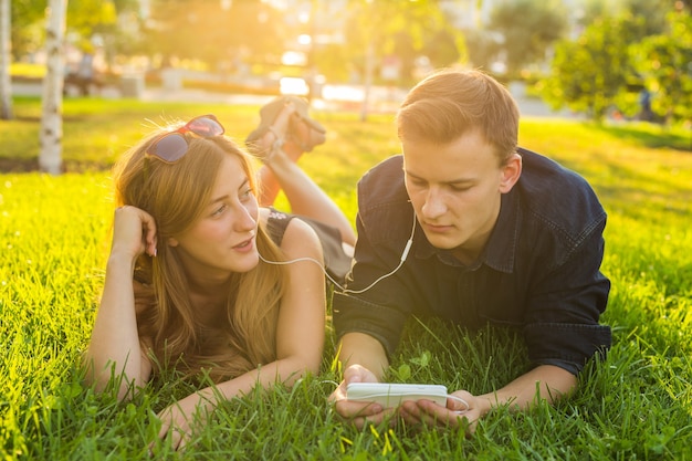 Liefdevolle jong koppel in zomer park luisteren muziek.