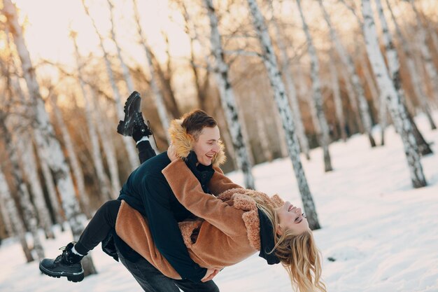 Liefdevolle jong koppel wandelen spelen en plezier hebben in winter forest park