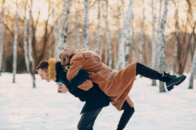 Liefdevolle jong koppel wandelen spelen en plezier hebben in winter forest park