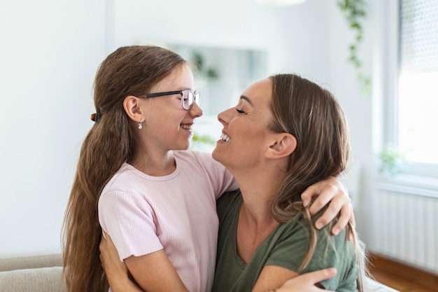 Liefdevolle jonge moeder lachen omarmen lachende schattige grappige kind dochter genieten van tijd samen thuis, gelukkige familie alleenstaande moeder met klein kind meisje plezier spelen voel vreugde knuffelen en knuffelen