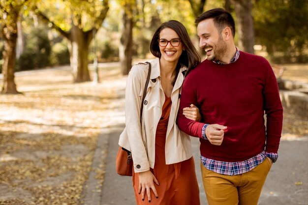 Liefdevolle jonge vrouw en man wandelen in stadspark hand in hand