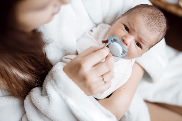 Liefdevolle moeder die haar pasgeboren baby thuis draagt boven raamverlichting