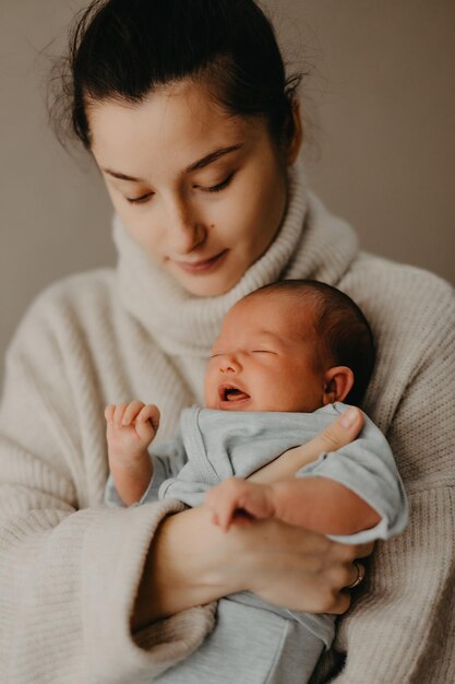 Liefdevolle moeder die haar pasgeboren baby thuis draagt helder portret van gelukkige moeder die schattig babykind op handen houdt moeder die haar kleine 1 maanden oude dochter knuffelt