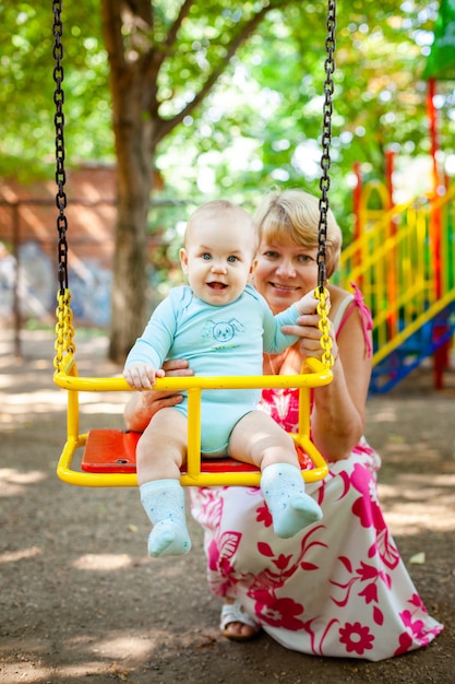 Liefdevolle moeder hugs haar zoontje in de speeltuin. Portret van een mooie moeder met baby