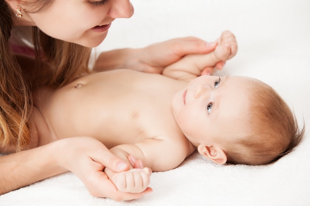 Liefdevolle moeder spelen met pasgeboren baby.