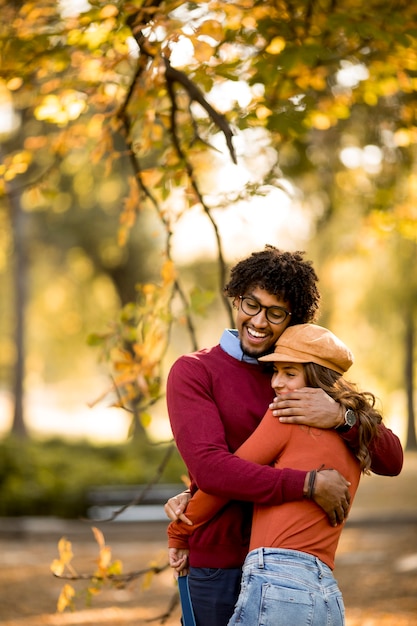 Liefdevolle mooie paar Afro-Amerikaanse man en blanke vrouw wandelen in het herfstpark