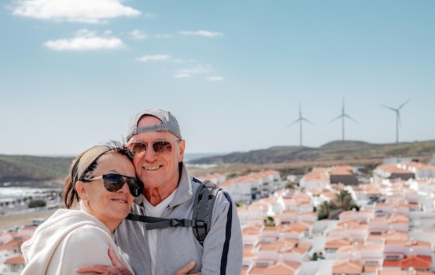 Liefdevolle oude senior familie paar hechting omarmen genieten van zonnige dag in openlucht Windmill achtergrond