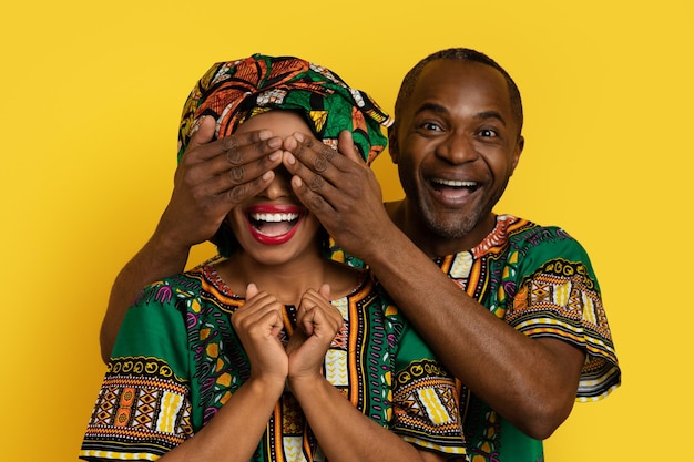 Liefdevolle zwarte man maakt verrassing voor vrouw die Afrikaanse outfits draagt
