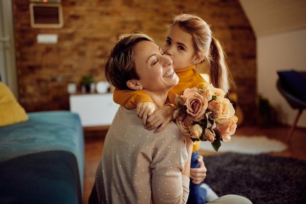 Liefhebbende dochter kust moeder terwijl ze haar een boeket bloemen geeft