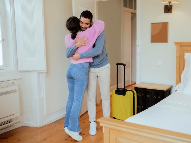 Liefhebbende echtgenoten knuffelen permanent met koffer in het interieur van de hotelsuite