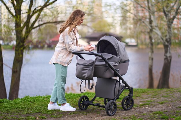 liefhebbende moeder die een fles met zuigelingenvoeding of moedermelk boven een kinderwagen vasthoudt