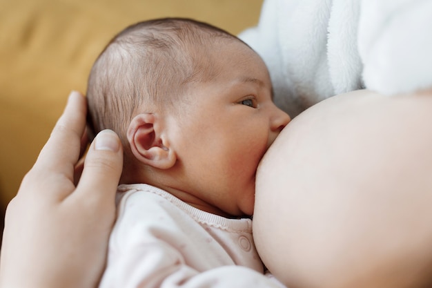 liefhebbende moeder die haar pasgeboren baby draagt, baby die moedermelk eet