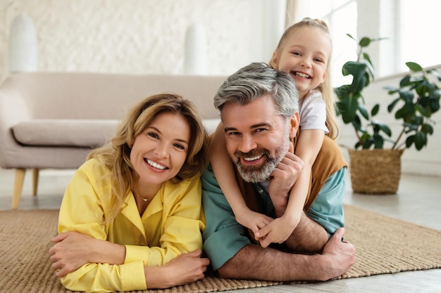 Liefhebbende ouders en dochter knuffelen liggend op de vloer thuis