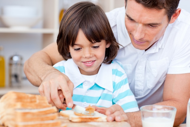 Liefhebbende vader en zijn zoon die jam op brood verspreiden