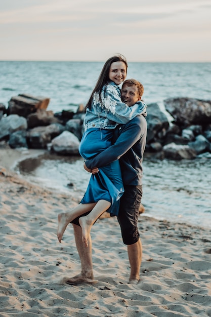 Liefhebbers lachen op het strand. De man draagt het meisje in zijn armen.