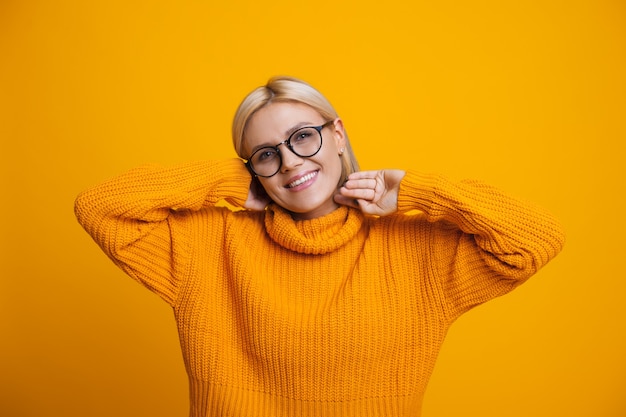 Lieve blanke vrouw met mooie trui raakt haar blonde haren tijdens het poseren