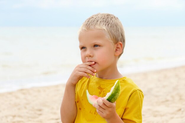 Lieve blonde jongen aan de kust diep in gedachten