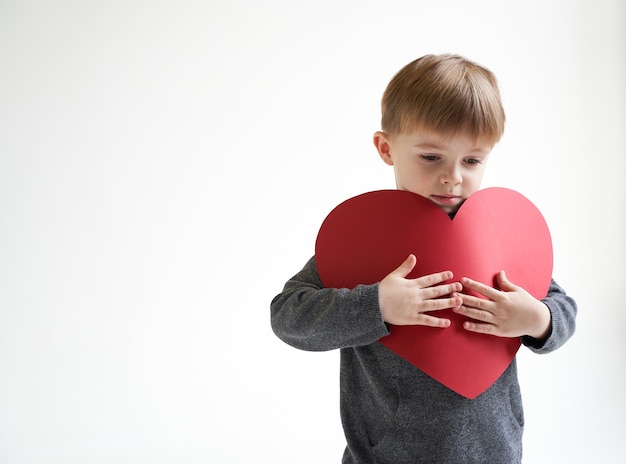 Lieve jongen met rood papier hart op witte achtergrond kinderen gezondheidszorg medische concept