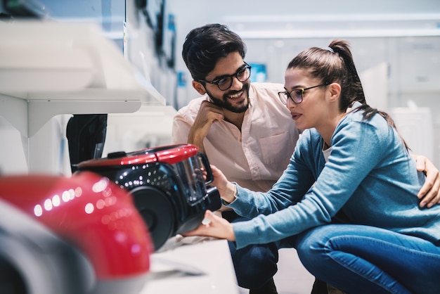 lieve man en vrouw die beslissen welke stofzuiger ze in de elektronische winkel kopen.