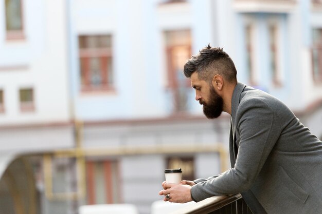 Life begins after coffee Bearded man enjoying morning coffee Businessman in hipster style holding takeaway coffee The best time of day to drink coffee Hipster with paper cup walking in city