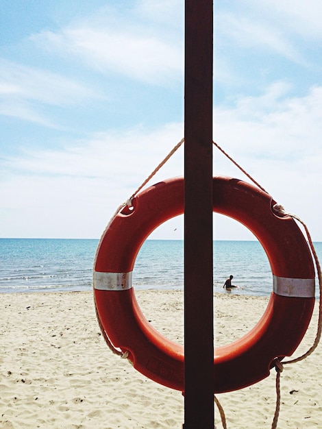 Foto cintura di salvataggio appesa a un palo contro il cielo sulla spiaggia