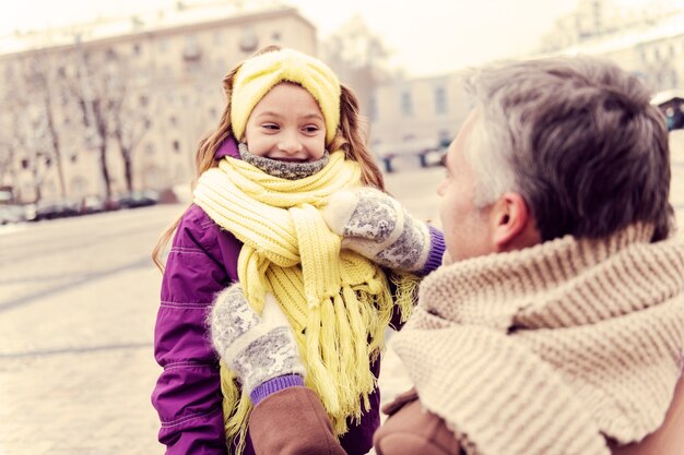 Life enjoyment. Beautiful kid expressing positivity while looking at her daddy