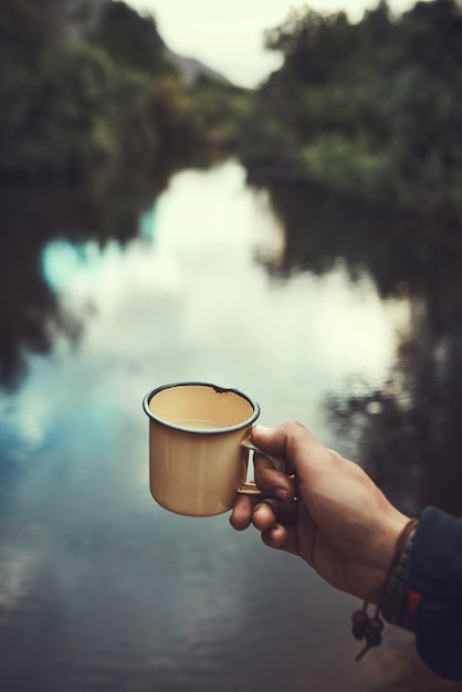 Life is better spent in nature Cropped shot of an unidentifiable man holding a mug with the river in the background